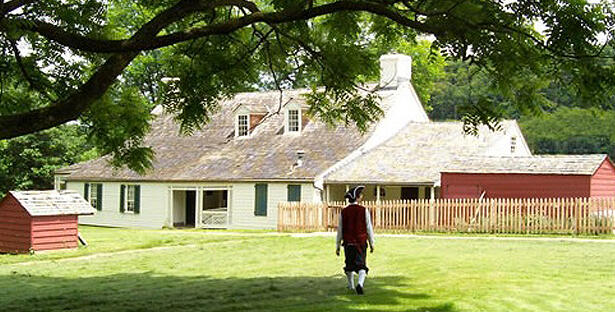 House at Woodville, photo courtesy of Pittsburgh History & Landmarks Foundation Photograph looking across lawn to the house at Woodville National Historic Landmark, a male figure dressed in colonial attire in the foreground